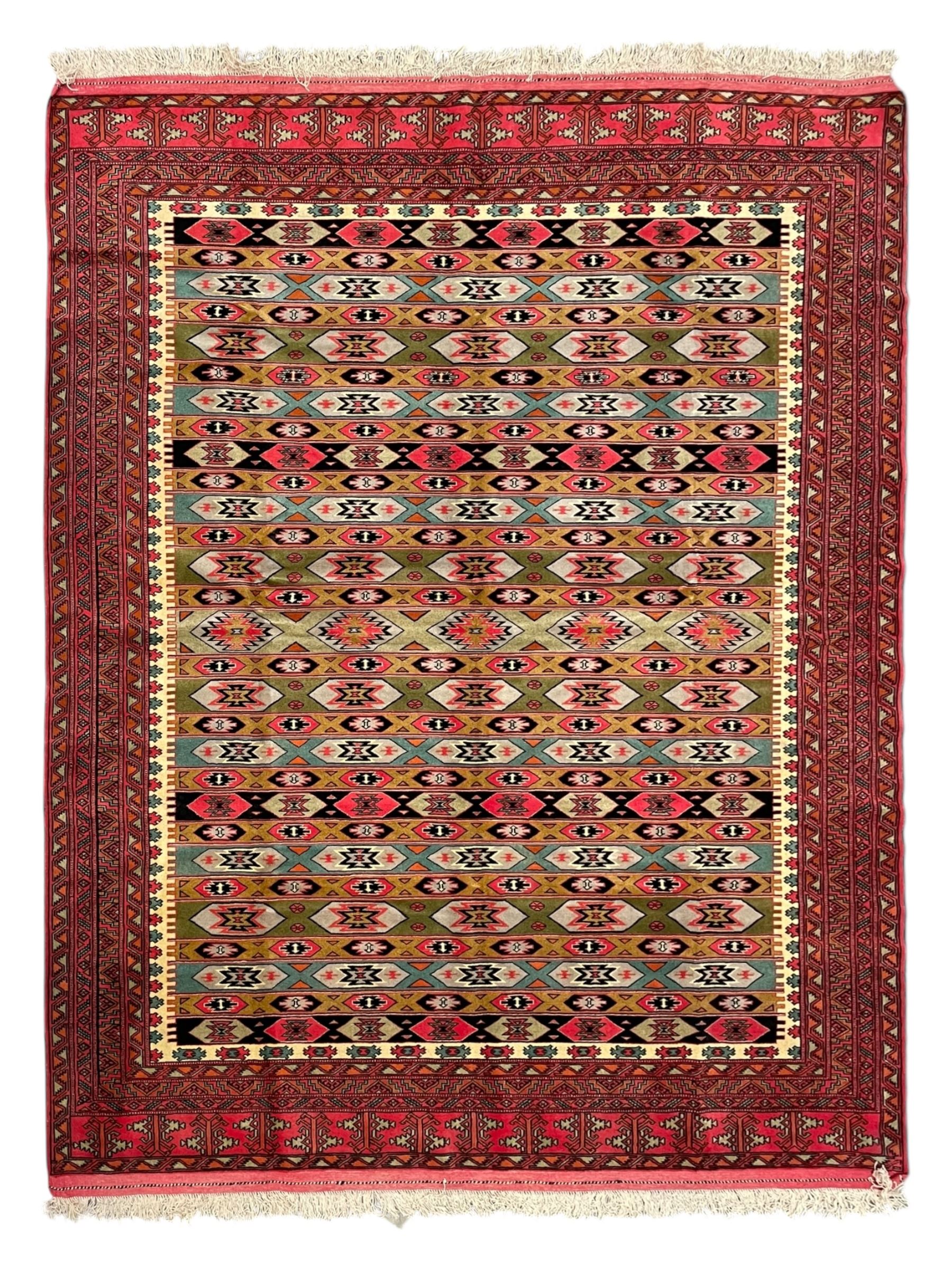 Turkaman red ground rug, the field divided into horizontal rows and decorated with geometric motifs, intricately pattern borders and end panels