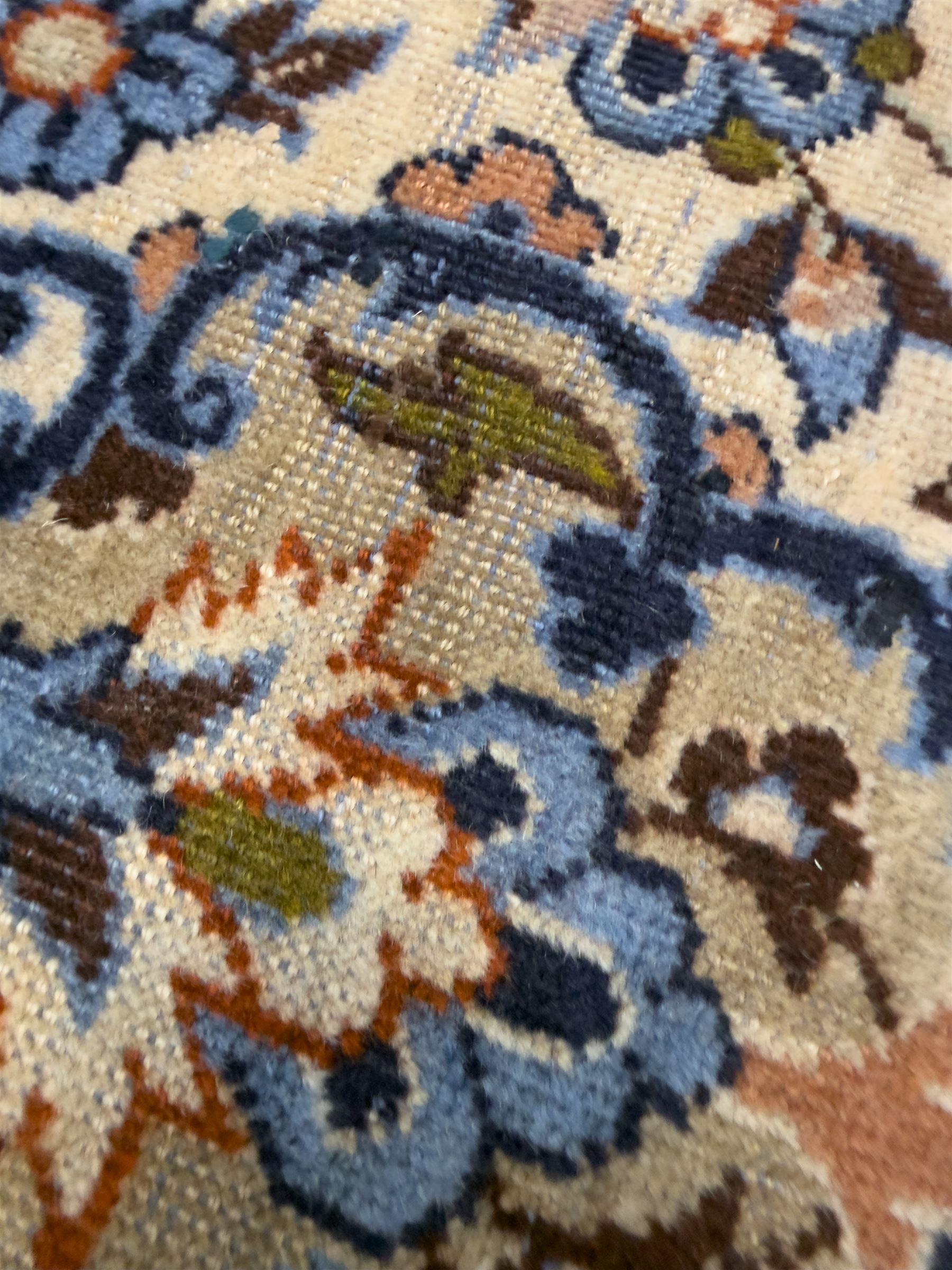 Central Persian Najafabad hand-knotted carpet, the ivory field with a central floral medallion radiating palmettes and arabesques in tones of blue, lilac and tan, enclosed by a wide navy border of scrolling vine and rosette motifs, with red spandrels and multiple guard stripes