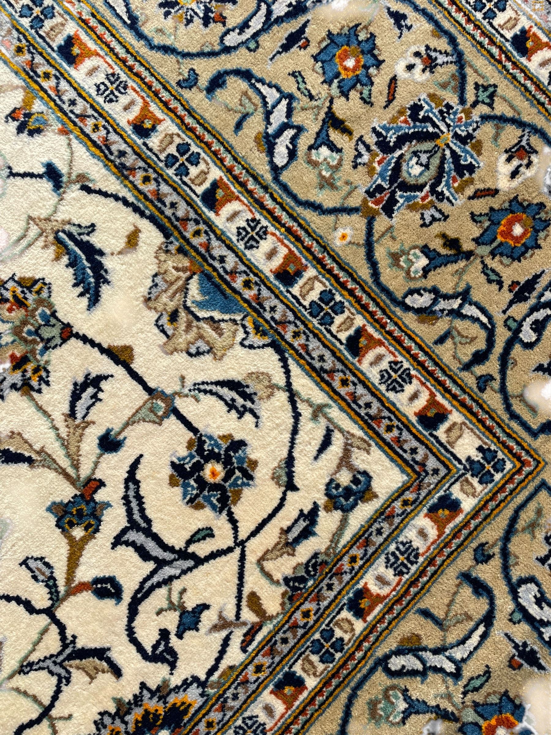 Persian Kashan ivory ground carpet, overall floral design, the field decorated with scrolling and interlaced leafy branches interspersed with palmettes, scrolling border decorated with stylised plant motifs, within floral pattern guard stripes 