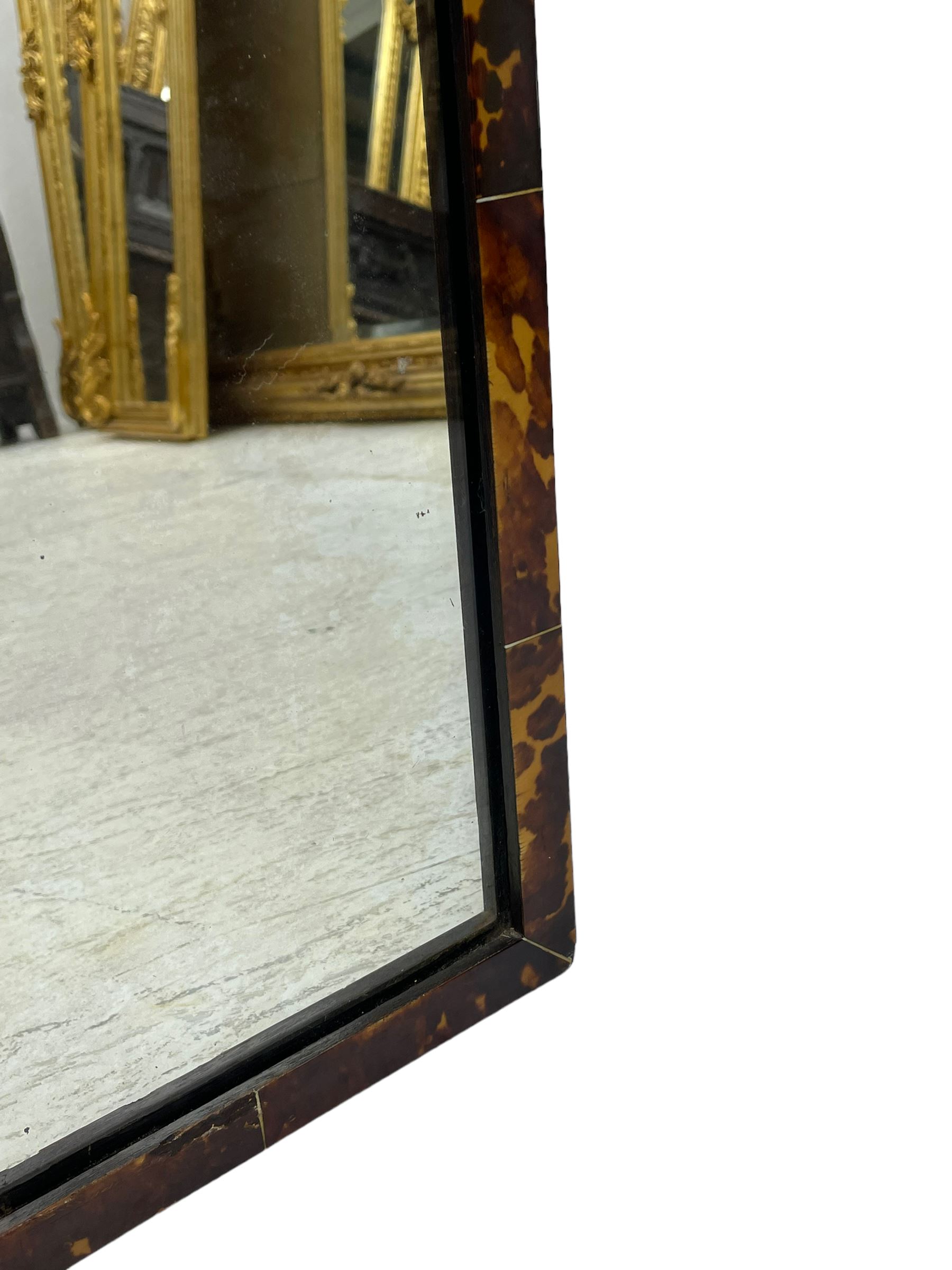 Early 20th century wall hanging tortoise shell framed mirror, of rectangular form, the upper half of the frame shaped and stepped surrounding a plain mirror plate