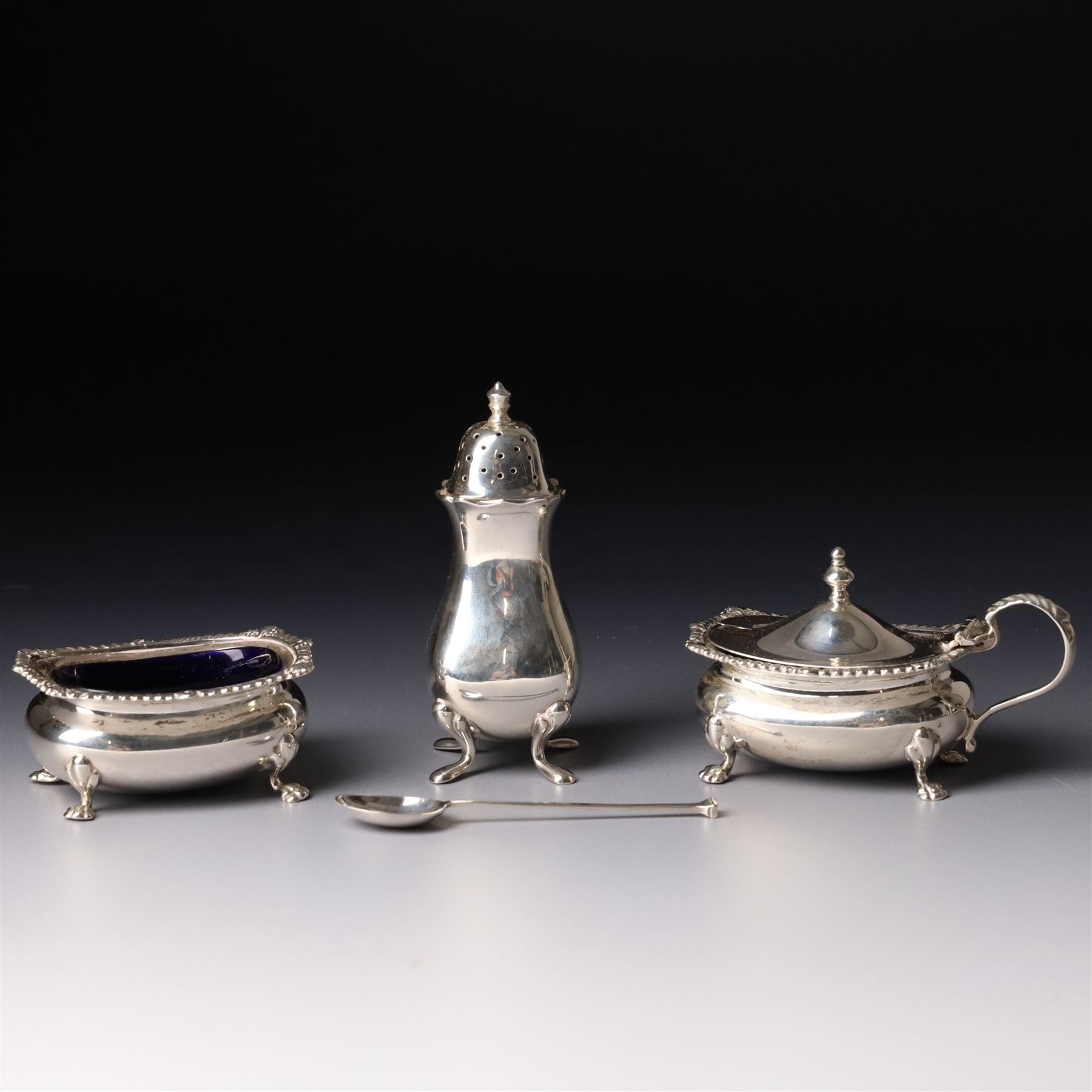 Silver salt and mustard pot with gadrooned edge on paw feet and with blue glass liners Birmingham 1919 and a similar pepperette