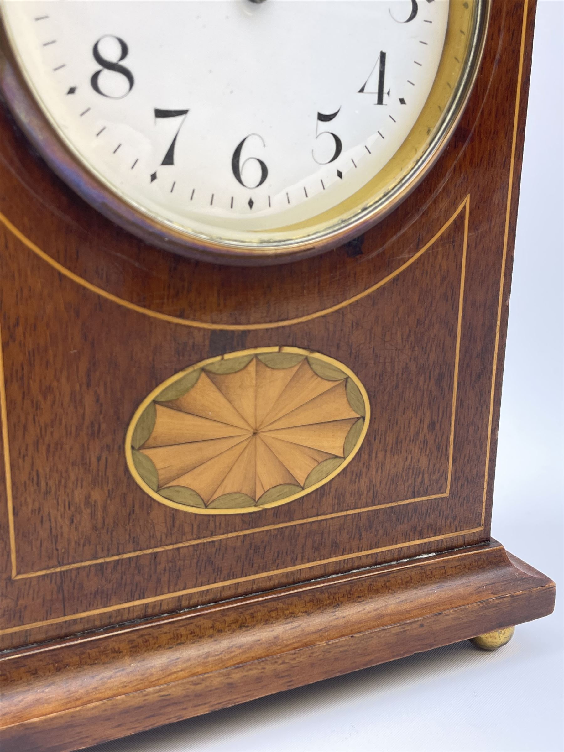 Edwardian inlaid mahogany mantel clock, stepped cavetto and arched top pediment, circular white enamel Roman dial signed 'A & J. Thompson, Scarborough', the front inlaid with fan motif, raised on globular brass feet, single train driven movement by 'R & Co. Paris'