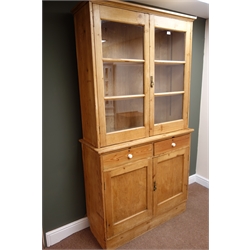  Traditional solid pine display bookcase on cupboard, two glazed doors enclosing shelves above two drawers and two cupboard doors, plinth base, W111cm, H209cm, D43cm  