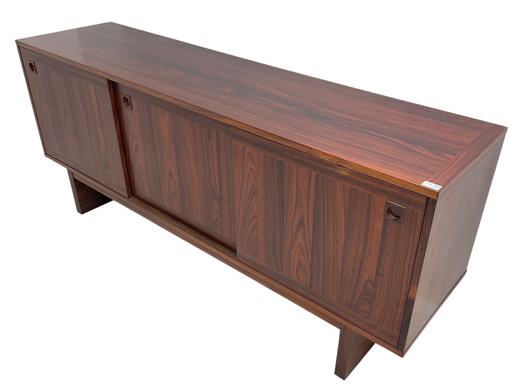 NH Chapman & Co Siesta - mid-20th century sideboard, fitted with three sliding doors, enclosing two drawers and shelves, raised on twin end supports