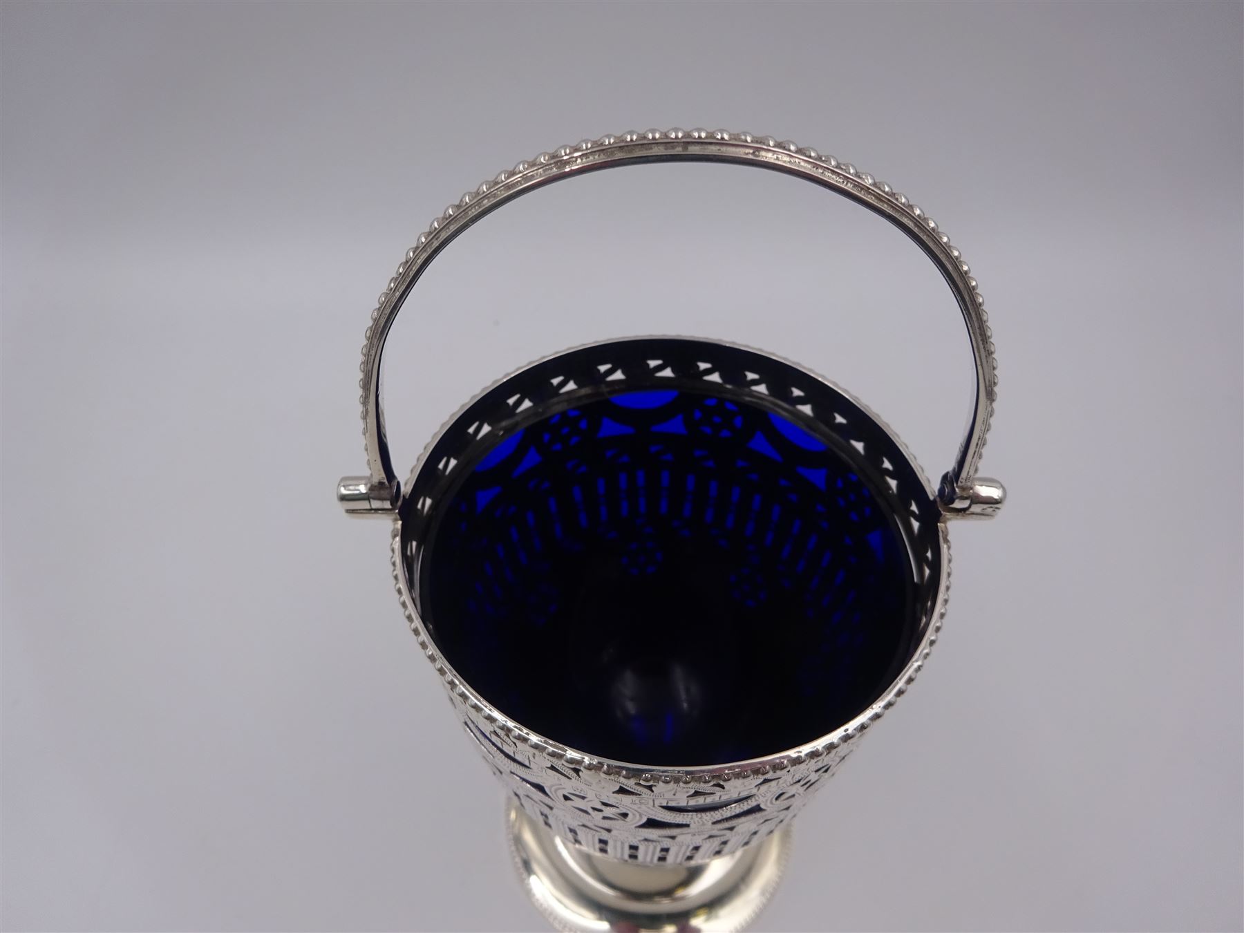 Edwardian silver swing handled sugar basket, with pierced and engraved star and foliate decoration to body, with beaded rim and handle, upon stepped circular base, hallmarked Thomas Hayes, Birmingham 1902, not including handle H10.8cm, with blue glass liner