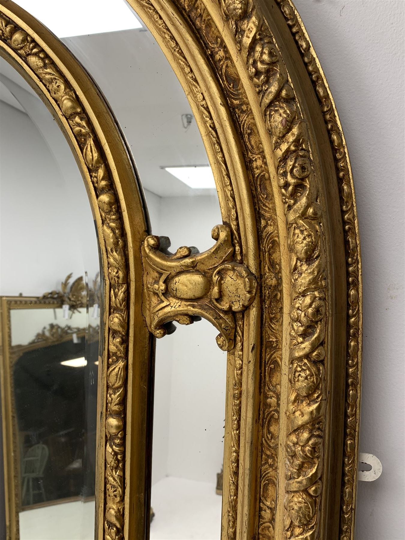 Gilt Rococo style mirror, arched top with central cartouche and oak leaf moulded pediment, floral and fruit moulded surround with segmented glass panels, bevelled central pane, c-scroll shell and acanthus leaf brackets