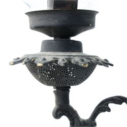 Late 19th century wrought metal hanging ceiling lamp, the ornate pierced central reservoir-form body with mounted eagle, three scrolling branches fitted with three clear glass chimney shades, suspended by decorative chains from a pierced ceiling rose