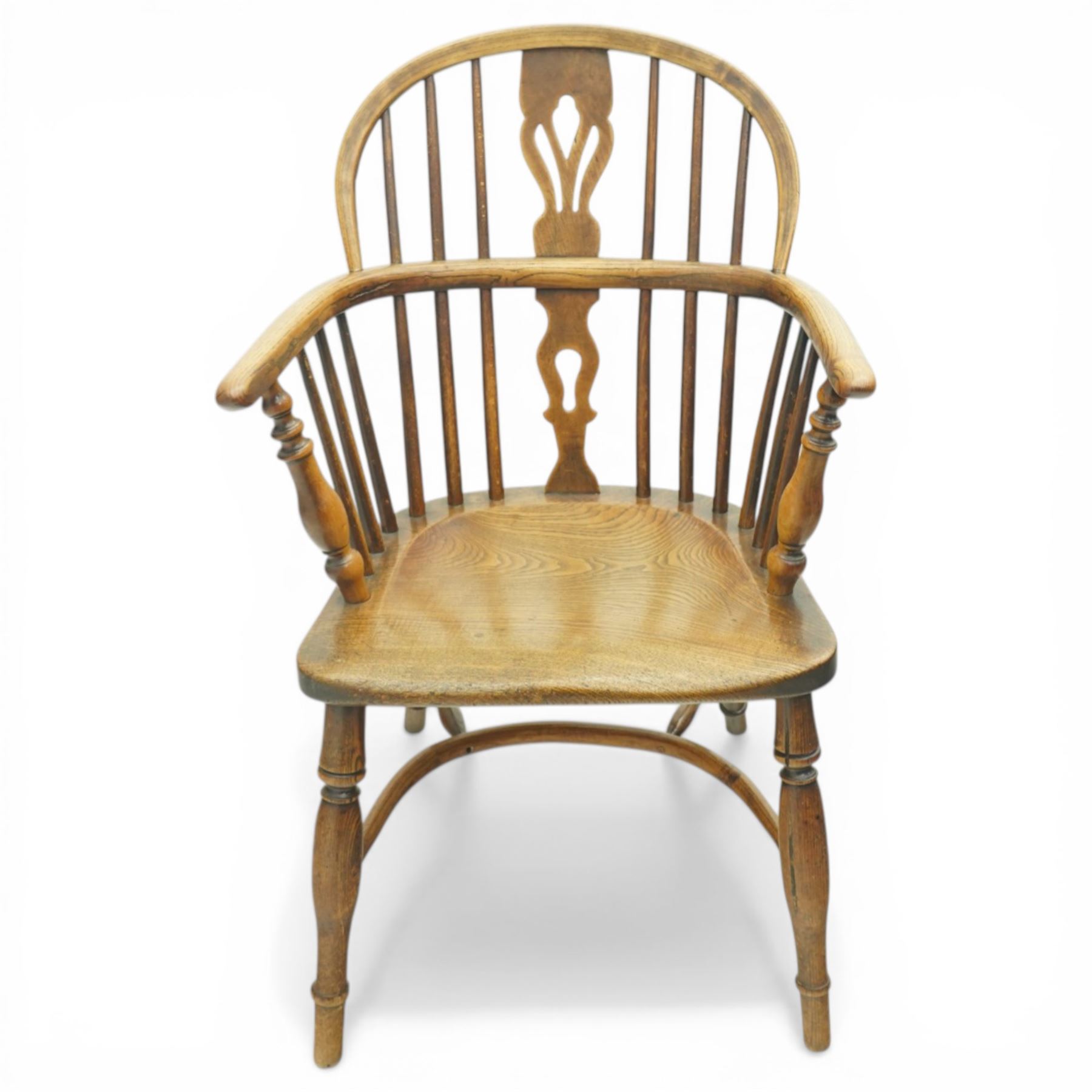 19th century low back elm Windsor armchair, hooped back with pierced central splat and radiating spindles, shaped arm bow over saddle seat, on turned supports united by crinoline stretcher