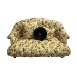 Victorian style two seat sofa, upholstered in beige ground floral floral pattern fabric, with scatter cushions, turned feet with brass castors