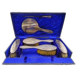 Edwardian silver mounted six piece dressing table set, comprising hand held mirror, two hair brushes, two clothes brushes, and a silver handled button hook, each of plain design and engraved with the letter N, hallmarked Charles S Green & Co Ltd, Birmingham 1909, contained within a fitted case with blue silk and velvet lined interior