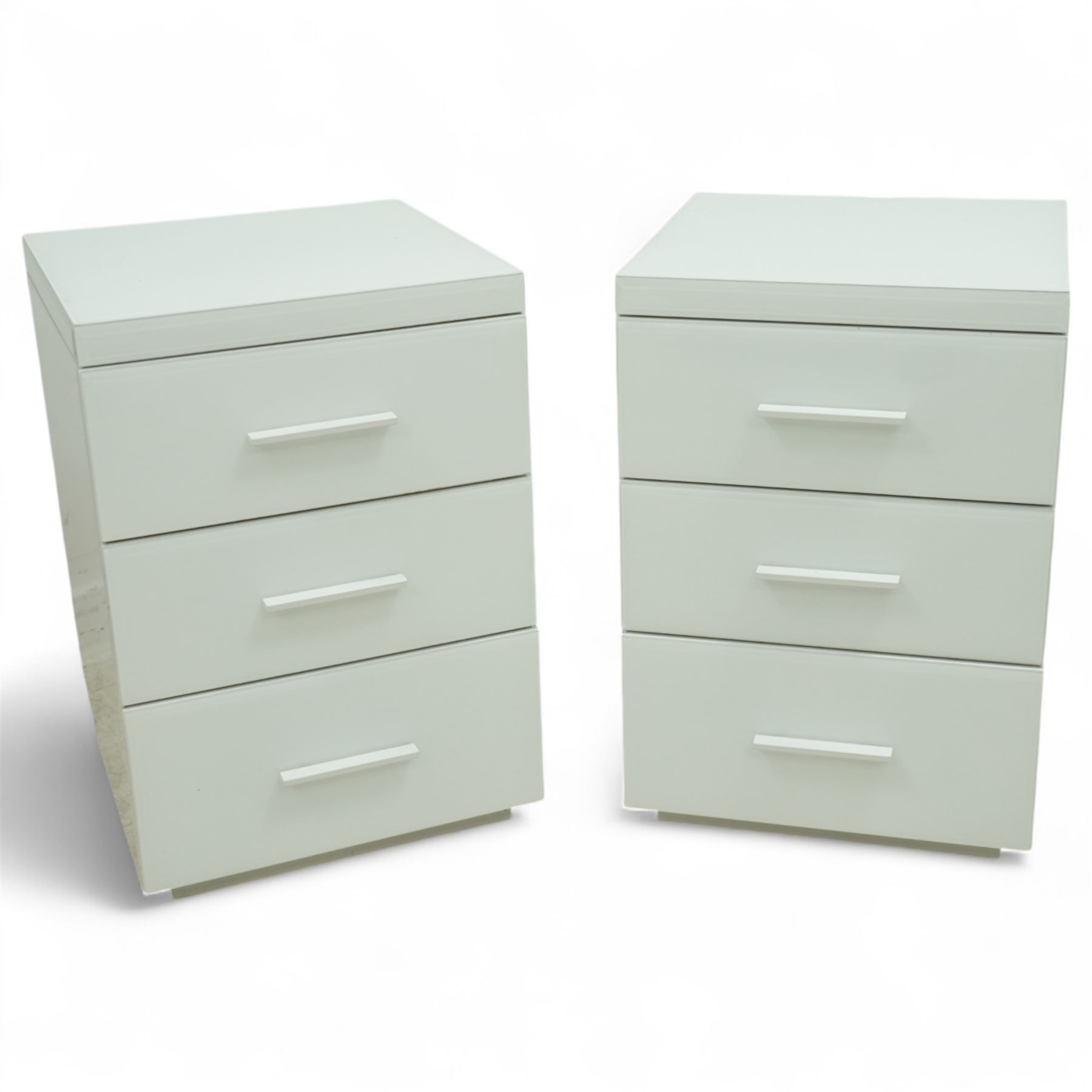 Pair of contemporary white and glass bedside chests, with square top over three drawers with integrated handles, plain sides and plinth bases