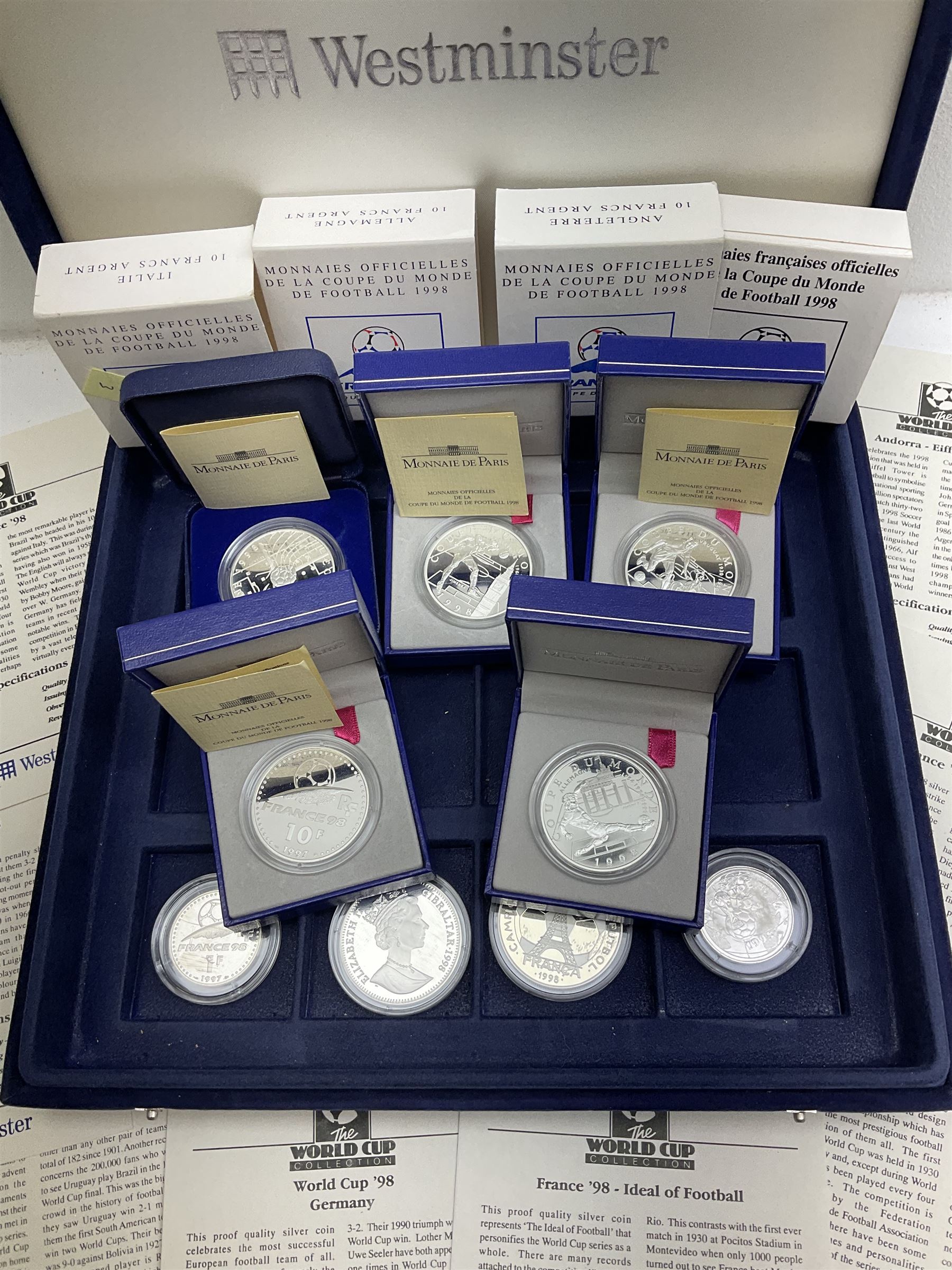 Nine commemorative coins relating to the France 1998 World Cup, some cased with certificates, in a blue coin storage box