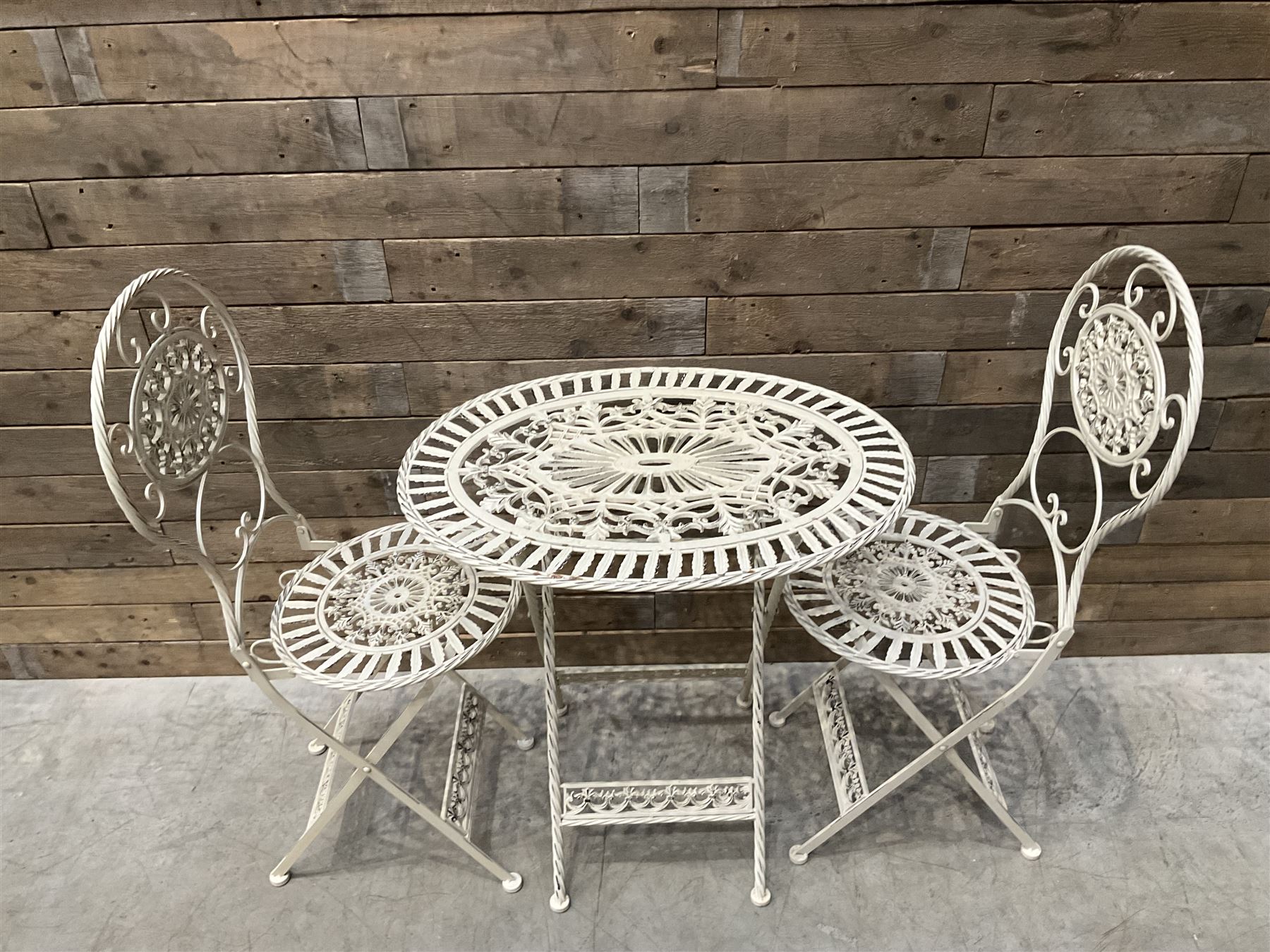 Cast metal bistro set including ornate oval garden table and two matching chairs