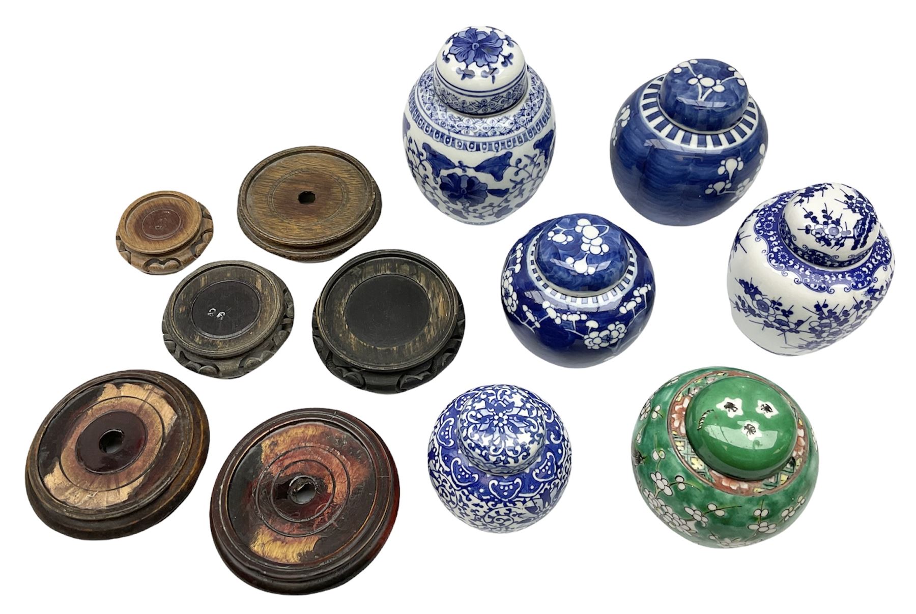 Six Chinese ginger jars, predominantly of blue and white design decorated with blossoming branches, all with lids, housed on various hardwood carved stands, some with character marks beneath
