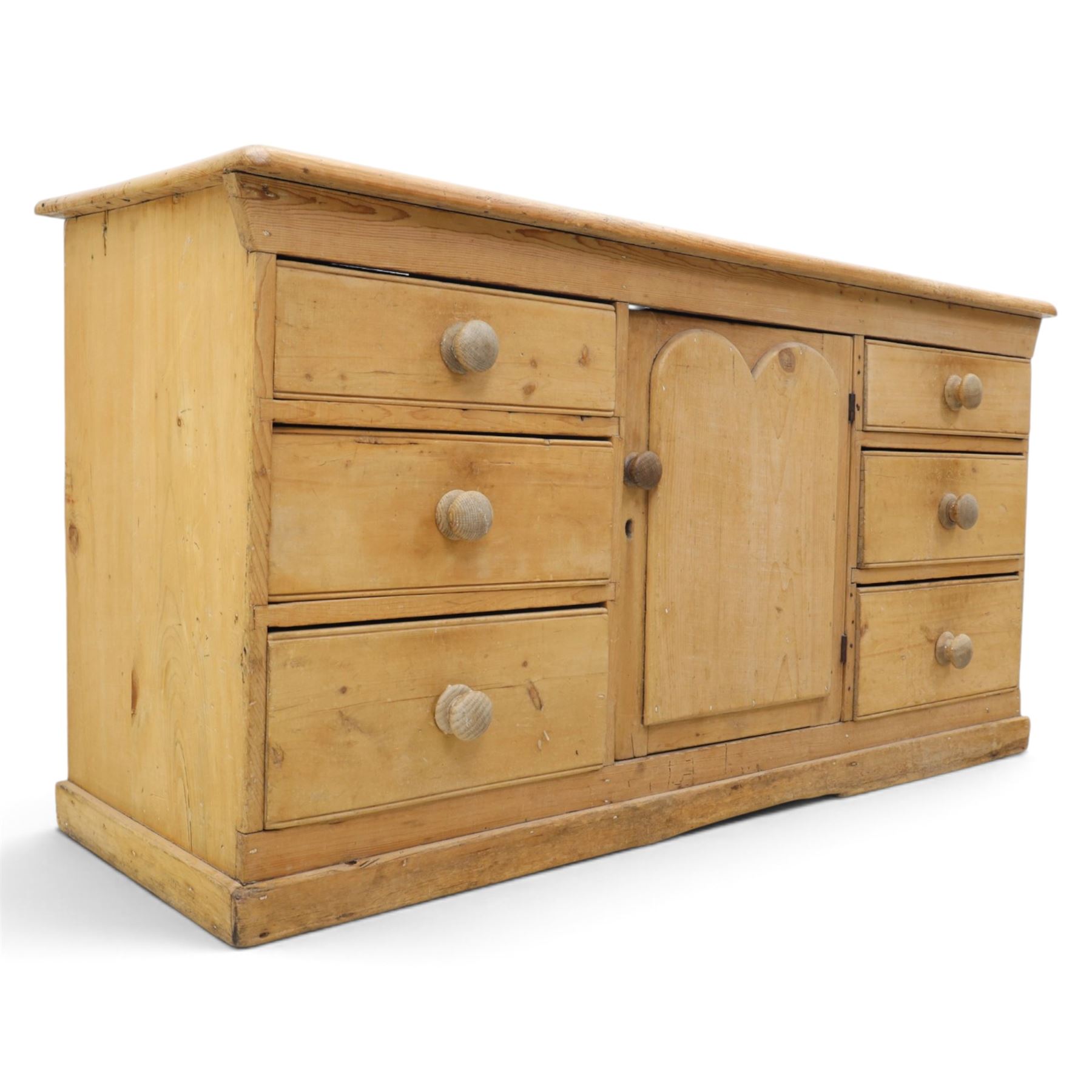 Victorian stripped pine sideboard, rectangular plank top rounded edges, with central cupboard door with shaped panel, flanked by two banks of three graduating drawers with turned knobs, raised on a plinth base 