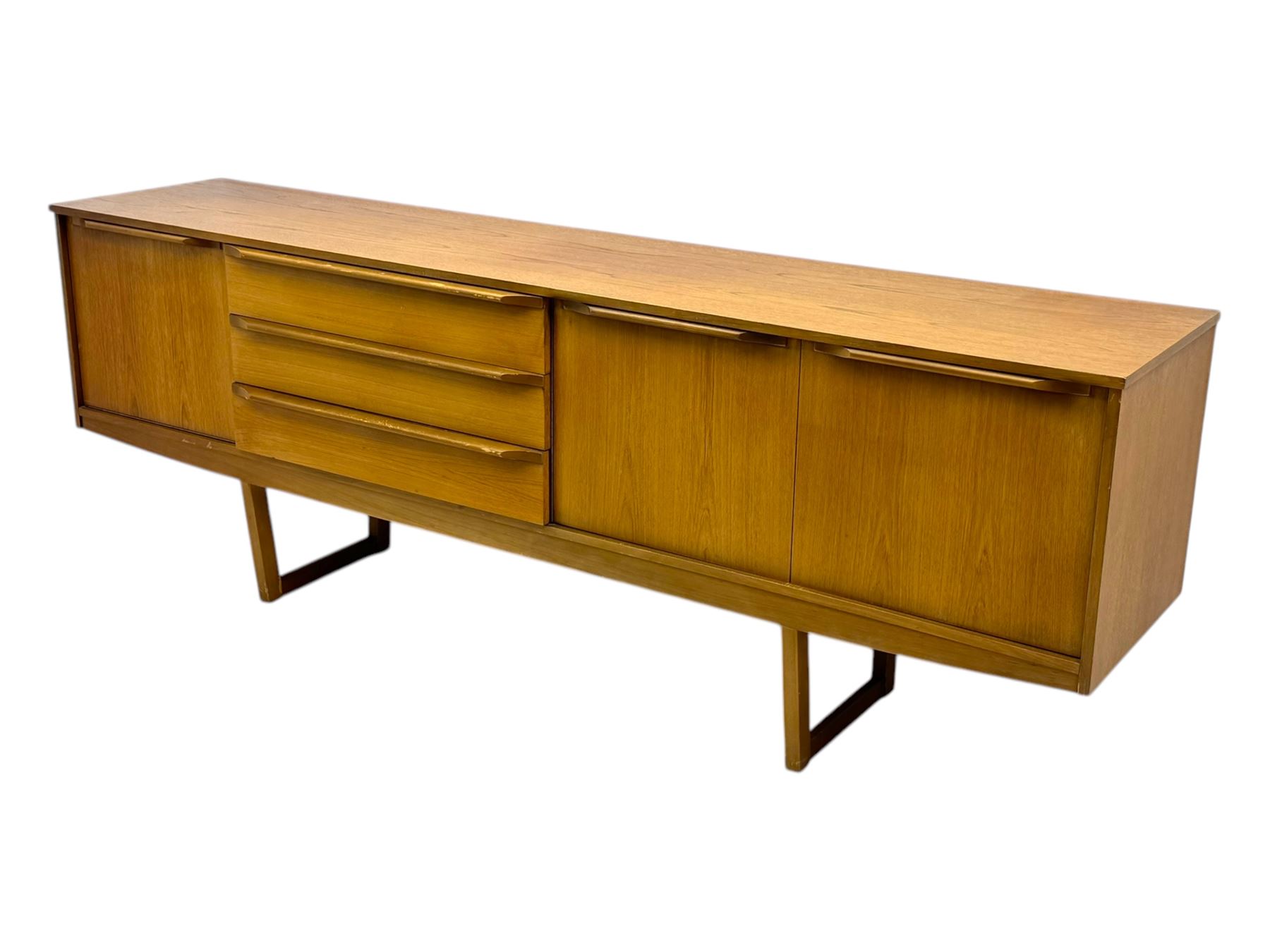 Mid-20th century teak sideboard, fitted with a fall-front cupboard, three drawers including a green baize-lined cutlery drawer, and a double cupboard, with integrated handles, on sleigh supports