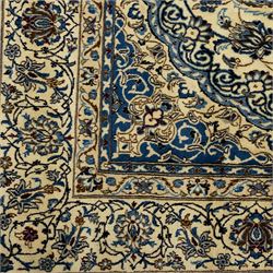 Central Persian Nain hand-knotted carpet, ivory ground, with silk highlights, centred by a shaped floral medallion with pendants, surrounded by scrolling foliate and floral motifs incorporating rosettes, palmettes and delicate vine work in blue, cream and beige tones, enclosed by blue spandrels and an ivory border with repeating palmettes and meandering vines, flanked by floral guard stripes, with cotton fringes
