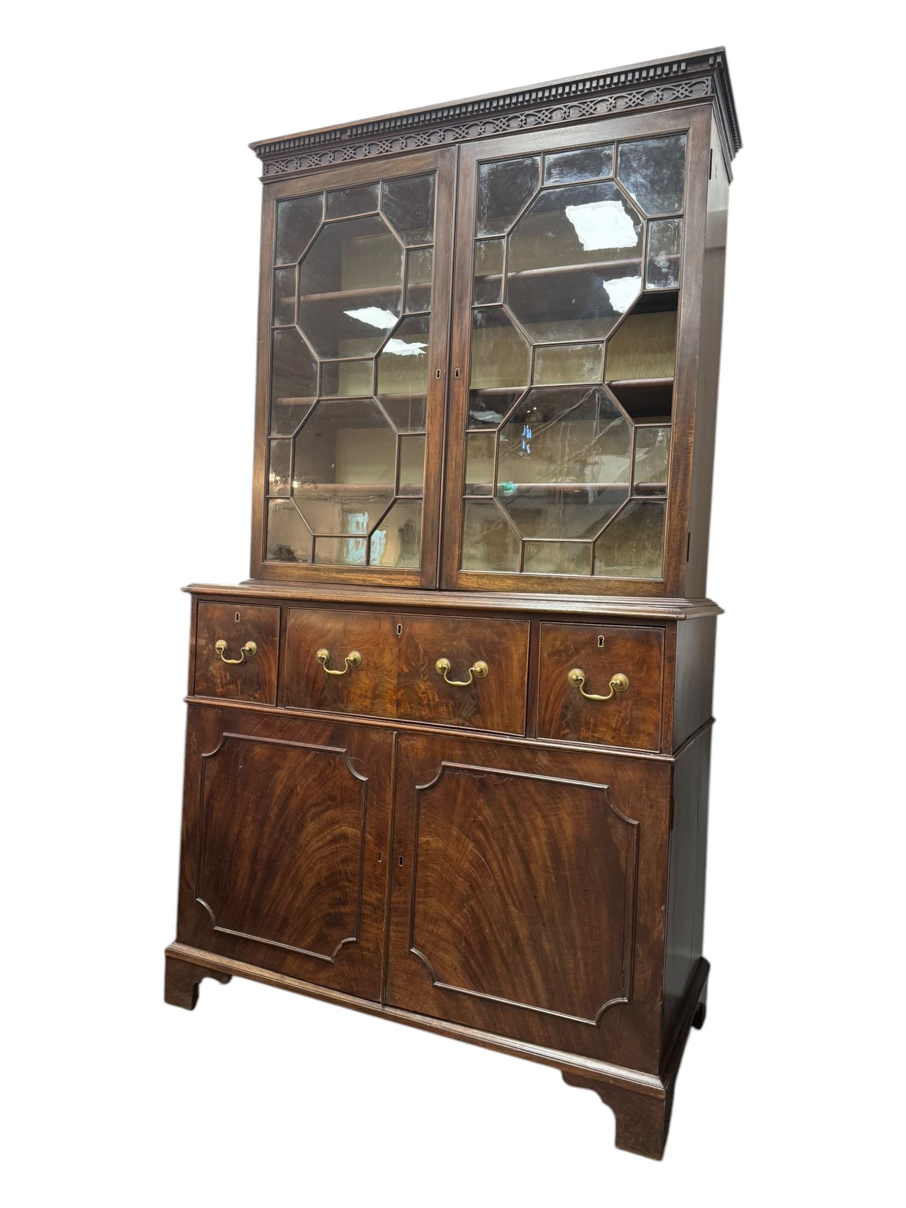 George III mahogany bookcase secretaire, dentil cornice over blind fret work frieze, enclosed by two astragal glazed doors, central secretaire drawer with fall front enclosing leather writing surface and small drawers, two flanking short drawers over double cupboard, on bracket feet