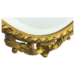 Oval gilt wall mirror, with bevelled edge plate within a moulded frame cast with acanthus scrolls and foliate decoration, pierced cartouche crest and apron, flanked by scrollwork handles