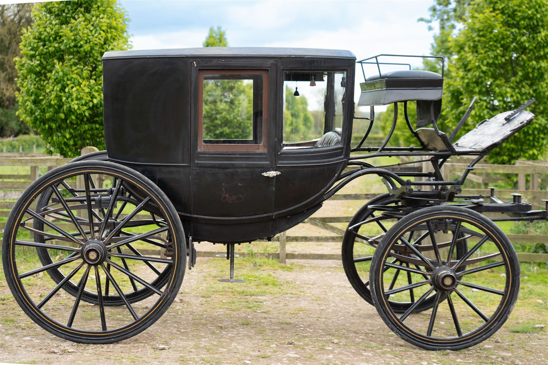 Town Coach by John Marstons Birmingham - Ex Film

A black painted five glass Town Coach by John Marston's Carriage Works Ltd, Birmingham, with enclosed glazed passenger compartment, curved front glass, external coachman's box seat and pole for driving with a pair of horses. The carriage has a timber coach body with buttoned black leather interior, blue upholstered seat cushions, plated exterior door handle, maker plates to the body and step, and John Marston marked hub caps. Mounted on black painted wooden spoked wheels with rubber tyres, leaf spring suspension, underbody turntable steering and iron fittings throughout.
Featured on the film set of 'Victoria' with Jenna Coleman

Features

• Black painted enclosed coach body
• Glazed passenger compartment with five windows
• Curved front glass
• Buttoned black leather interior
• Blue upholstered seat cushions
• External coachman's box seat
• Timber coach body
• Wooden spoked wheels
• Rubber tyres
• Leaf spring suspension
• Underbody turntable steering
• Pole for pair of horses
• Iron foot steps
• Plated exterior door handle
• Maker plates for John Marston's Carriage Works Ltd, Birmingham
• John Marston marked hub caps
• Featured on the film set of Victoria with Jenna Coleman

Dimensions:
Overall length: 390 cm
Width: 190 cm
Height: 214 cm

Wheel Diameters:
Front wheels: 104 cm
Rear wheels: 134 cm

Seating:
Coachman's box: 2
Passenger compartment: 4