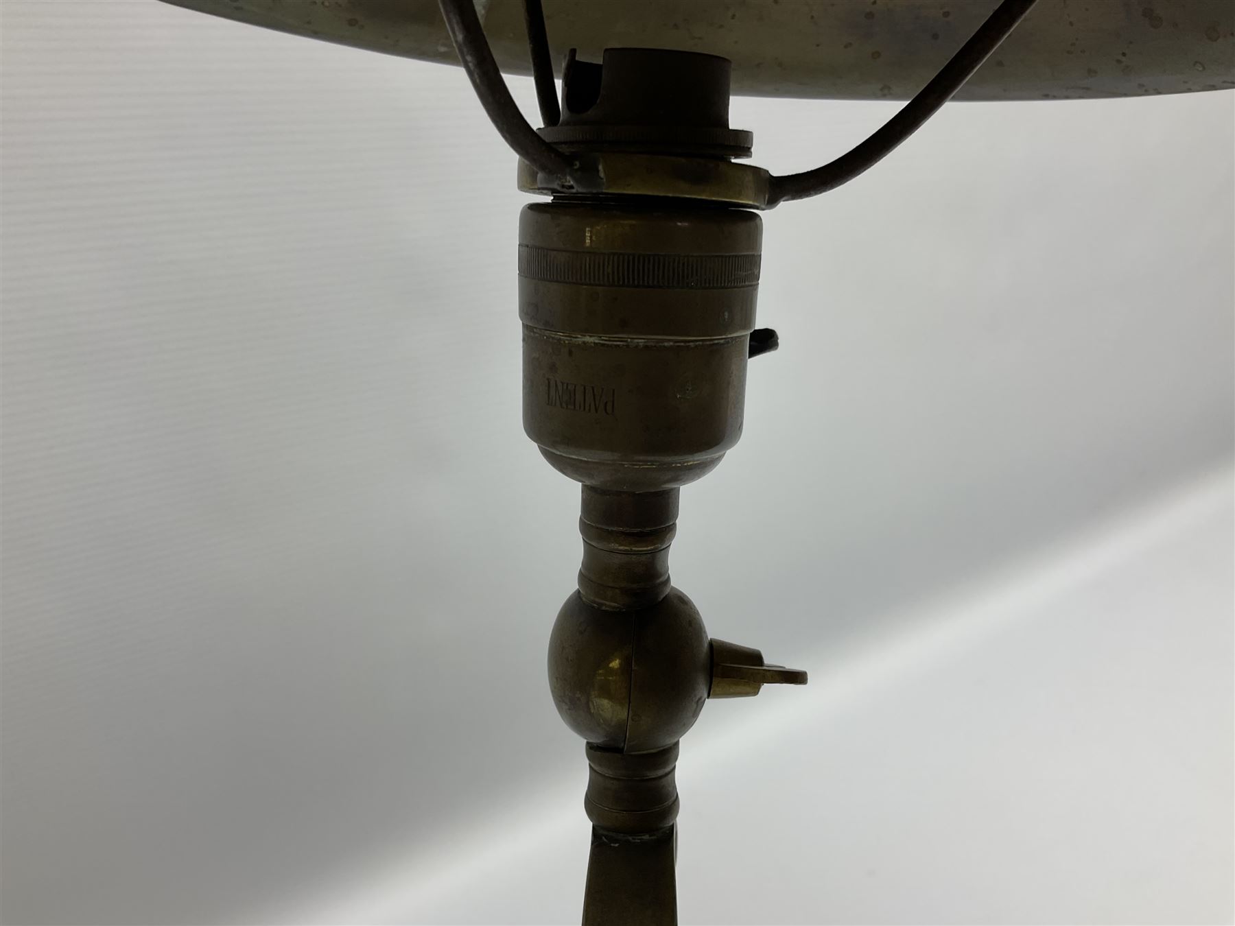 Arts & Crafts Jesson, Birkett & Co, brass table lamp or wall light, designed by Thomas Birkett, the tapering stem with adjustable ball pivot supporting a conical shade with tapering final with ball terminal, upon a circular domed base pierced for wall mounting, shade positioned upright overall H57cm

Often misattributed to Arthur Stansfield Dixon for Birmingham Guild of Handicraft, this particular lamp was designed by Thomas Birkett.
In the late 1890's Birkett worked as a metalwork at the Birmingham Guild, before later joining the Faulkner Bronze Company which went on to become Jesson, Birkett & Co in 1904. The lamp features in lighting catalogues from the firm under the model no E490.

