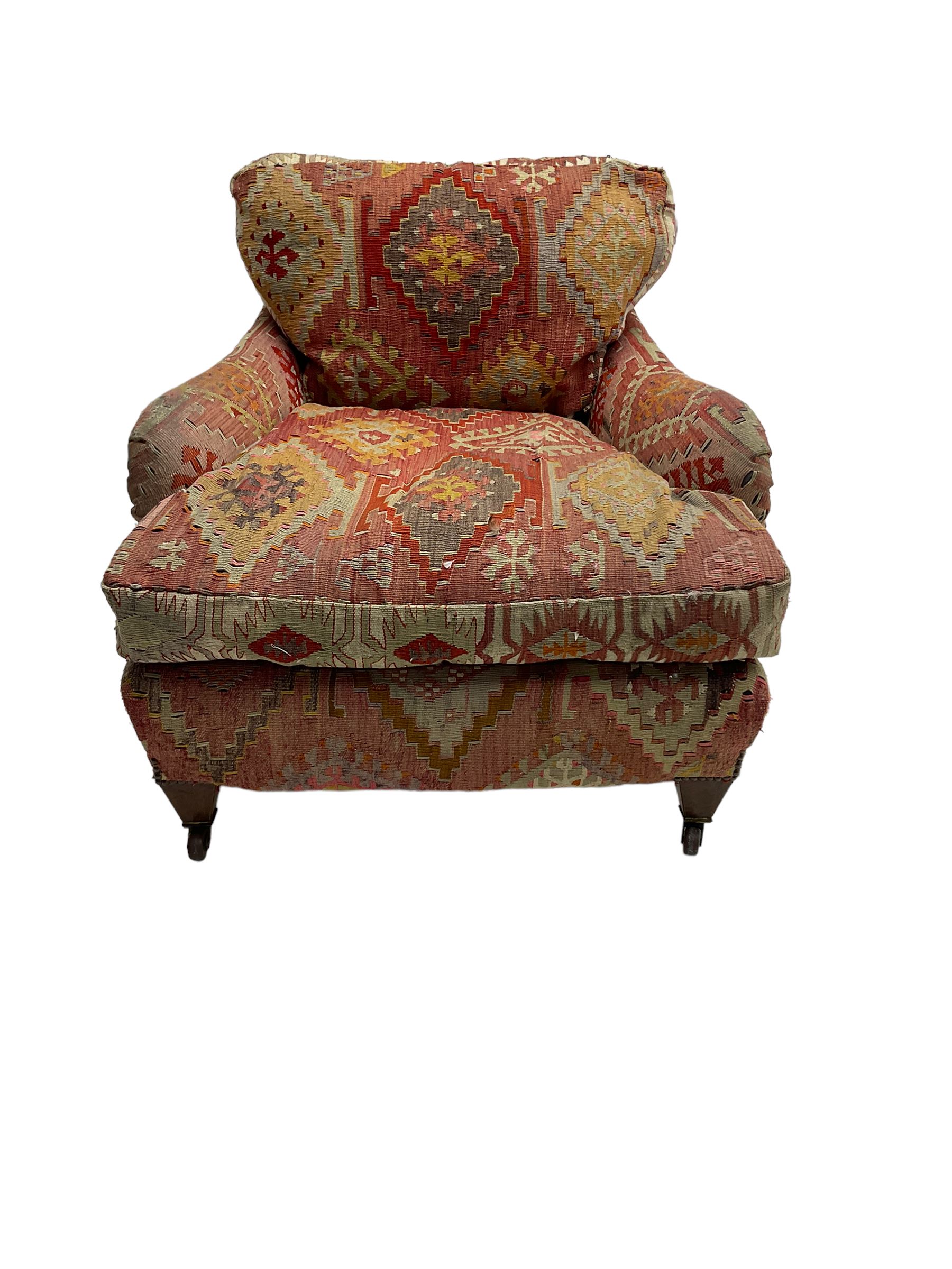 Early 20th century Howard style armchair, upholstered in Kilim fabric with sprung seat, hardwood frame, square tapering supports with brass and ceramic castors