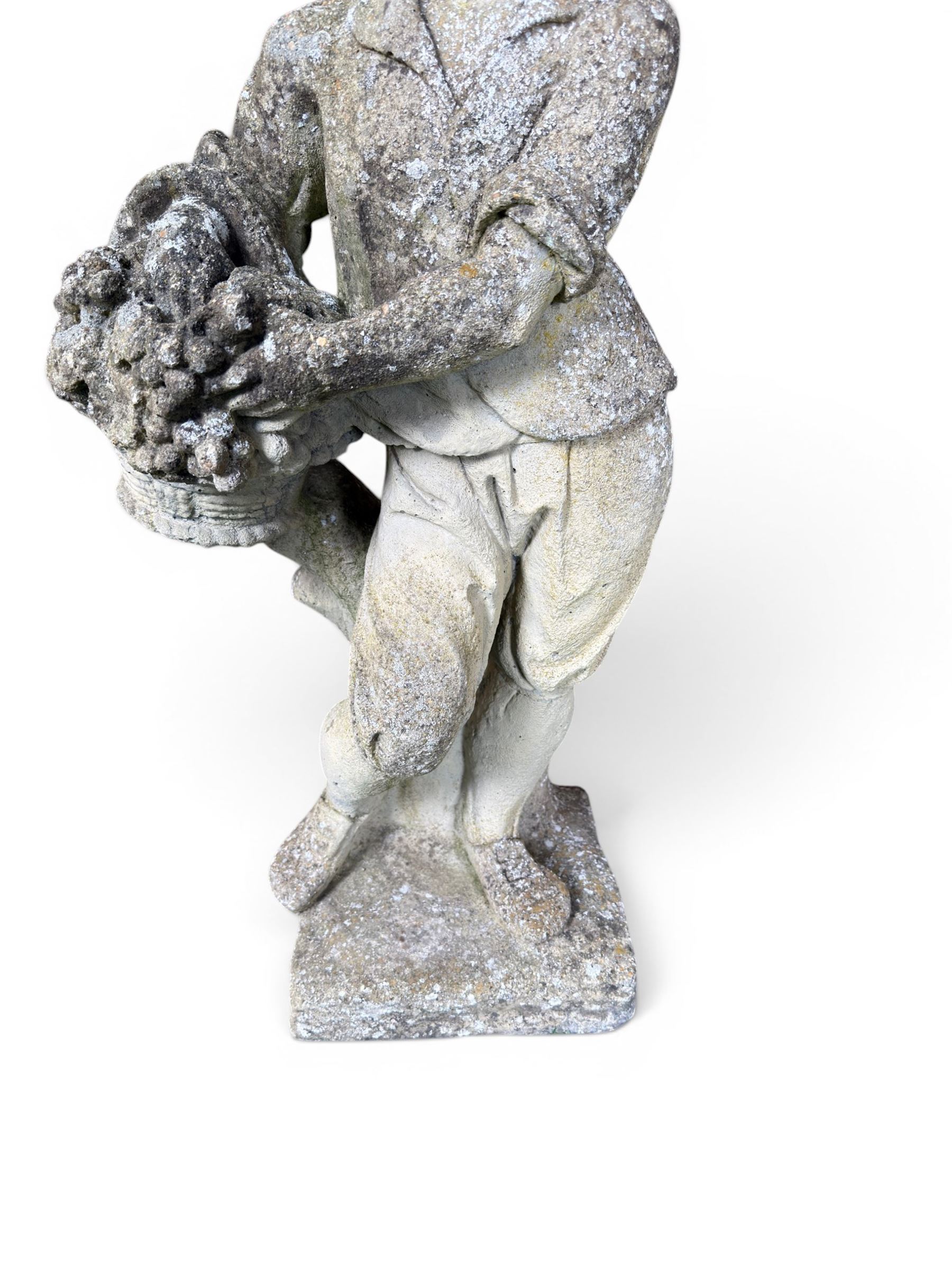 Weathered cast stone garden figure depicting a child holding a fruit basket
