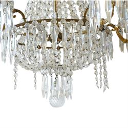 Regency Country House cut-glass and ormolu six light chandelier, the outer shaft with ormolu foliate moulding hung with octagonal and drop pendants, the impressive central shaft with cascading drops of cut-glass, the scroll branches with hob-nail cut candle holders and wax pans, with central similarly cut terminal
Provenance: property of a nobleman
