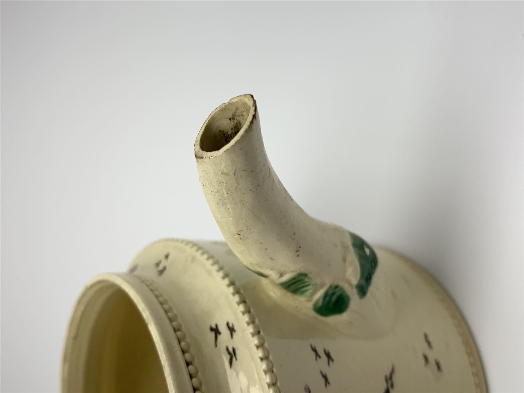 18th century creamware teapot, probably Leeds, with reeded entwined handle and floral finial to the cover, the body with hand painted polychrome decoration of figure to one side, and floral spray to the other, collectors paper label beneath inscribed Leeds Pottery, H11.5cm