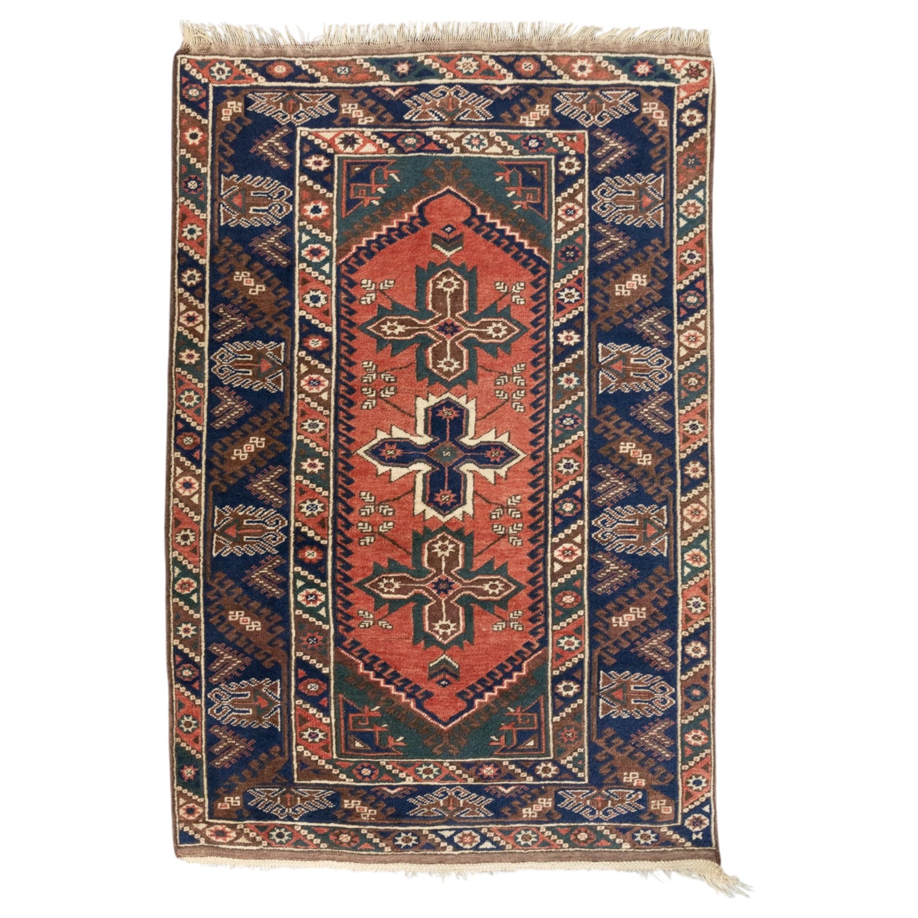 Caucasian Kazak rug, red field with three bold geometric medallions in dark blue, cream and brown, scattered tribal motifs, broad indigo border decorated with stylised hooked forms and multiple narrow patterned borders