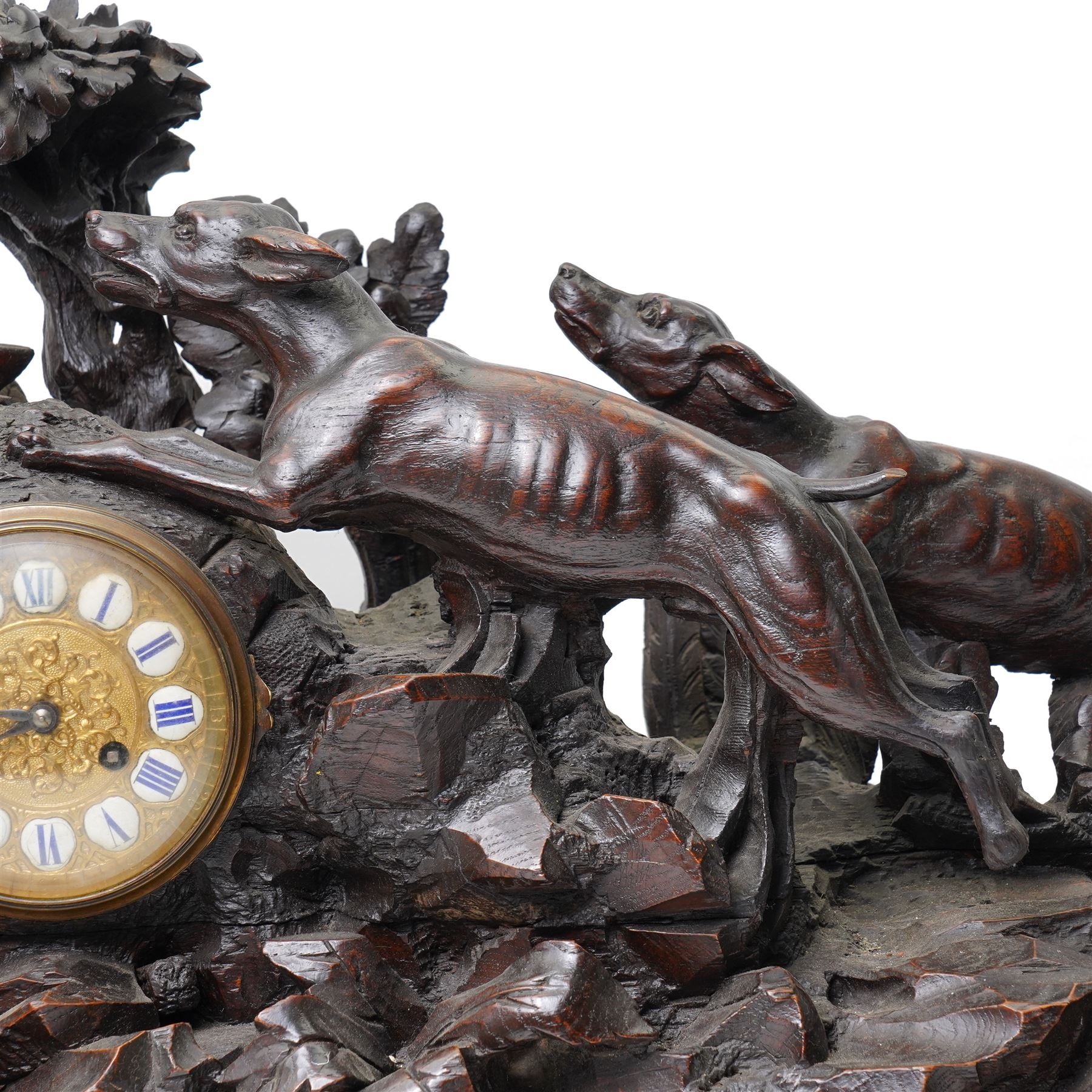 19th-century-8-day German Black Forest mantel clock c1880, with a carved oak case depicting a hunting scene with a stag pursued by hounds amidst rockwork and oak foliage, fitted with a French Parisian movement with a cast brass dial enclosed within a glazed brass bezel with a pendulum adjustment arbor, cartouche blue-on-white enamel  Roman numerals, engraved five minute Arabic's and contrasting steel Fleur-di-Lis hands, twin train going barrel movement with a recoil anchor escapement and countwheel strike. With pendulum.  