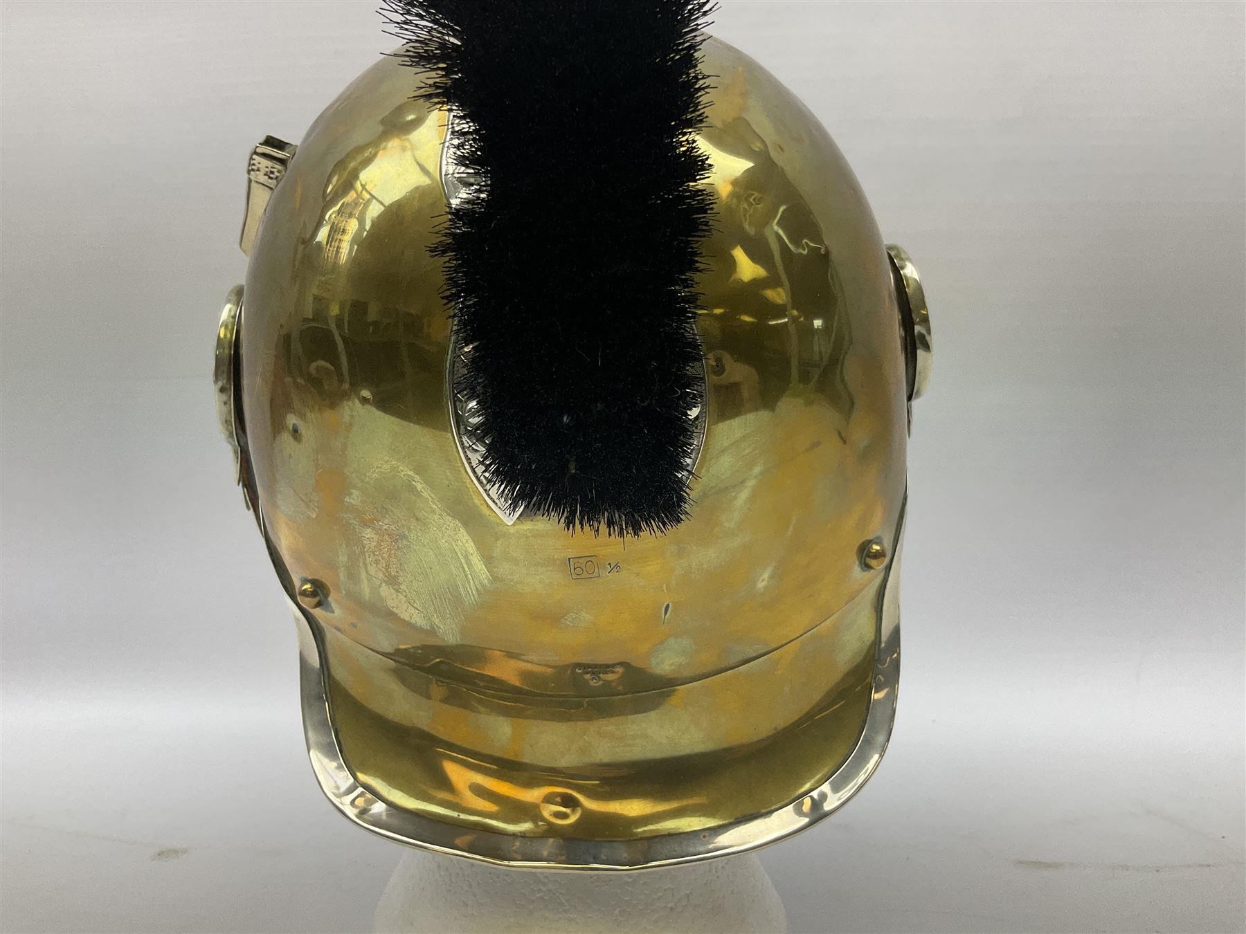 Early 20th century French mounted gendarme's helmet, brass with nickel-silver mountings, broad band embossed with fused grenade, high comb with the face of the gorgon Medusa at the peak and with a black horse hair crest, plume socket at the left, leather-backed nickel-silver chin scales with lion mask mounts.