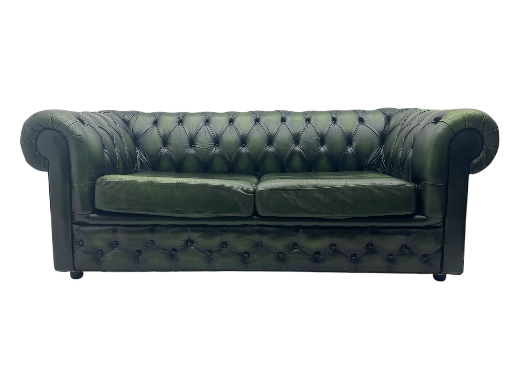 Two seat Chesterfield design sofa bed, upholstered in emerald green leather with deep-buttoned detailing, rolled arms, two loose seat cushions, and pull-out 