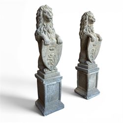 Pair of cast stone Heraldic lions, modelling in upright standing poses with flowing mane, each clasping an Armorial shield moulded with a crowned lion in their forepaws, raised on rectangular pedestals