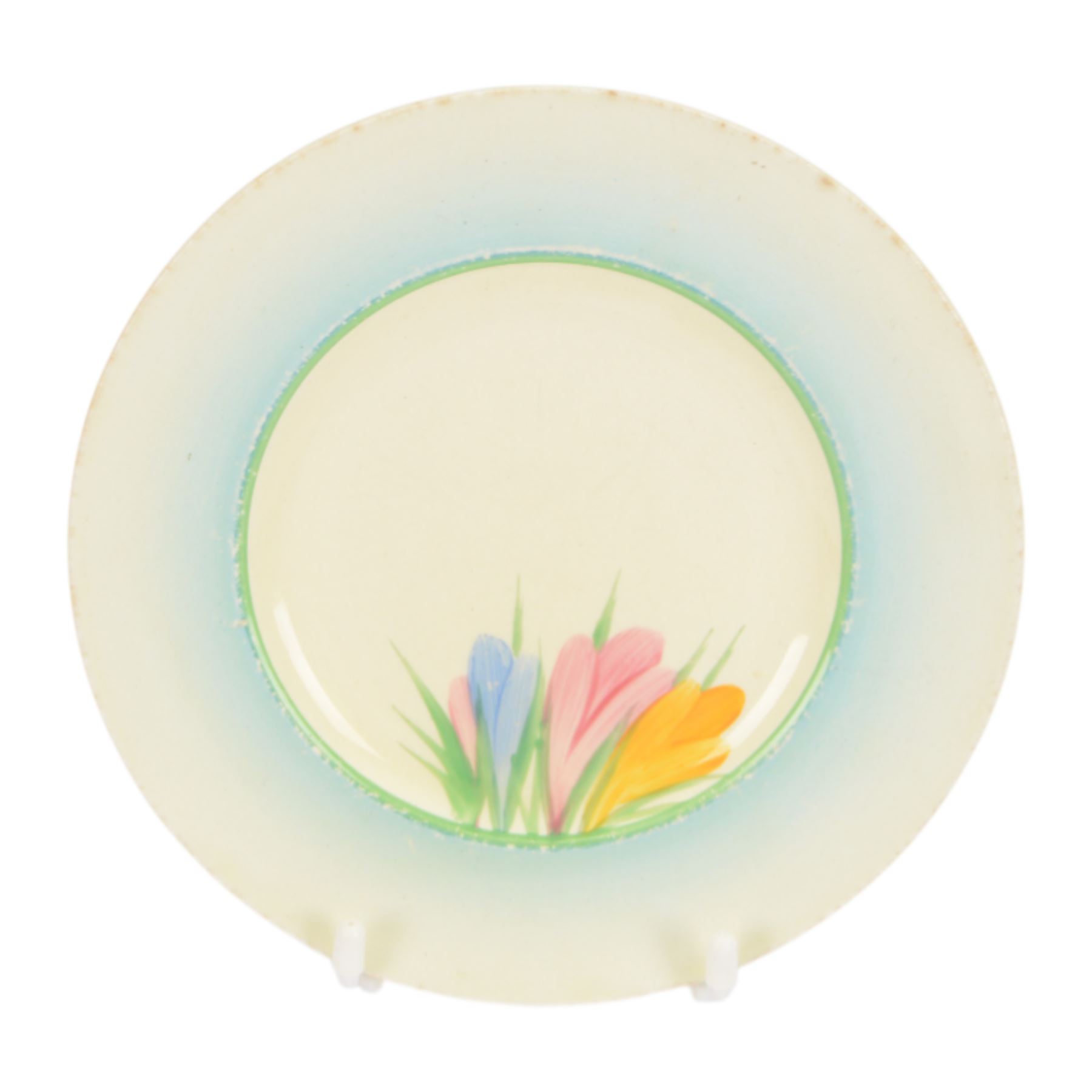 Clarice Cliff Orange Trees & House pattern side plate circa 1931, hand painted with a stylised tree and cottage landscape with orange and black banding, with printed mark beneath, together with a Clarice Cliff Spring Crocus pattern side plate, with printed mark beneath, largest D20cm  