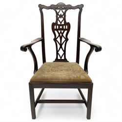 19th-century Chippendale Revival design mahogany oversized high-back armchair, serpentine crest carved top rail above pierced back splat with interlaced ribbon carving and geometric fretwork design, and outward scrolling arms above drop-in needlework seat on square chamfered legs 