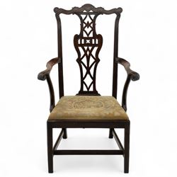 19th-century Chippendale Revival design mahogany oversized high-back armchair, serpentine crest carved top rail above pierced back splat with interlaced ribbon carving and geometric fretwork design, and outward scrolling arms above drop-in needlework seat on square chamfered legs 