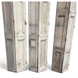Set of three French 19th century painted pine folding window shutters of tall form, each comprising two hinged leaves with three graduated raised and fielded panels, in antique cream-painted finish