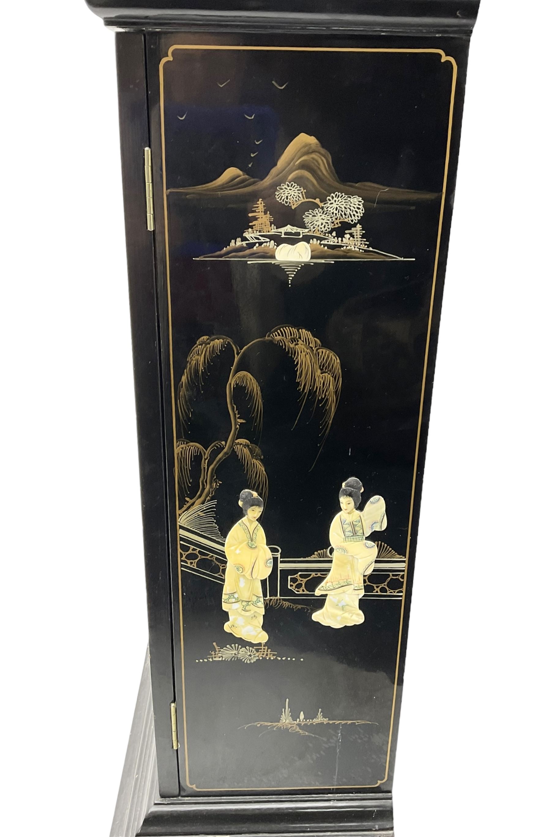 20th century 8-day chain driven black lacquered longcase clock - with a swans neck pediment and break-arch hood door, fully glazed trunk door displaying brass cased weights and pendulum, case sides, hood and plinth profusely decorated in gold relief and chinoiserie figures, brass break arch dial with an etched centre and silvered chapter ring, German two train movement striking the hours and half hours on two gong rods. With weights and pendulum.
