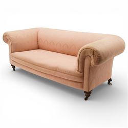 Victorian two seat sofa, upholstered in pink fabric, bowed form with scroll back and arms, raised on turned legs with castors