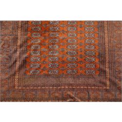 Bokhara hand-knotted carpet, terracotta ground with repeating rows of Tekke guls and geometric motifs, enclosed by multiple geometric borders, with silk highlights, fringed ends