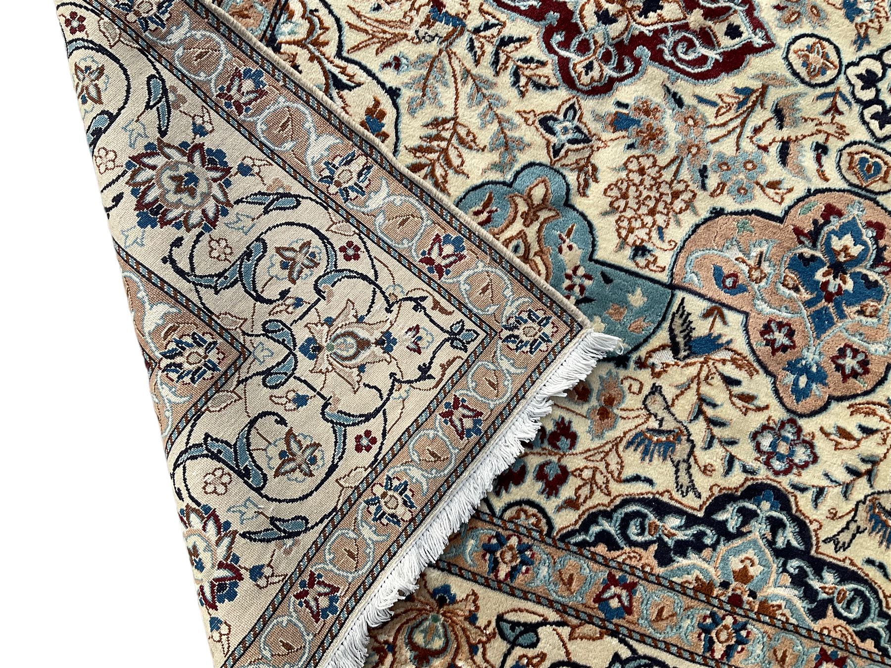 Persian Nain ivory ground rug, wool with silk inlay, the field decorated with stylised gul motifs with palmettes surrounded by interlacing foliate patterns, the guarder border decorated with repeating flower heads and scrolling vines