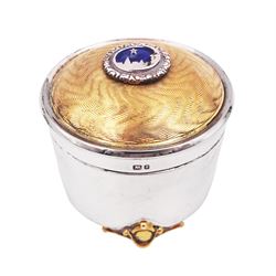 Modern silver limited edition Christmas music box, of circular form, with engine turned parcel gilt wave decoration and applied enamel roundel depicting Bethlehem, the North Star and a crescent moon to centre of hinged cover, upon three parcel gilt feet, with musical mechanism playing Silent Night, no. 94/500, H6.5cm