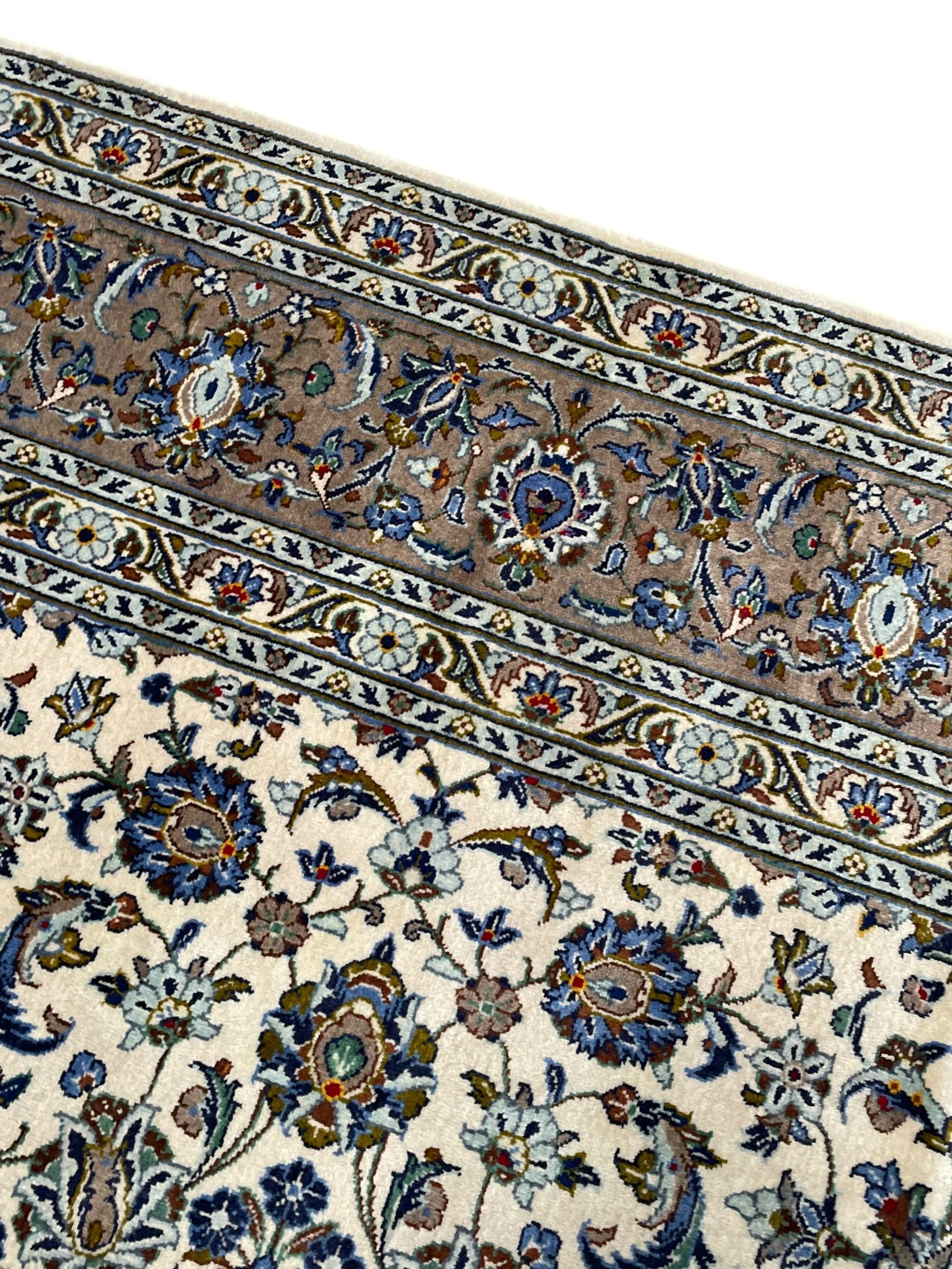 Persian Kashan ivory ground carpet, central medallion on a field of scrolling foliate branches decorated with palmettes, the border decorated with repeating stylised plant motifs, floral design guard stripes