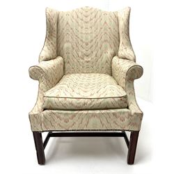Georgian style mahogany framed wingback armchair upholstered in a beige ground fabric, shaped cresting rail, scrolling arms, square fluted supports 