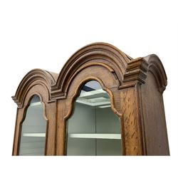 George III oak bookcase on bureau, the double arched top enclosed by two shaped glazed doors, fall-front concealing fitted interior, over four graduating cock-beaded drawers, on bracket feet