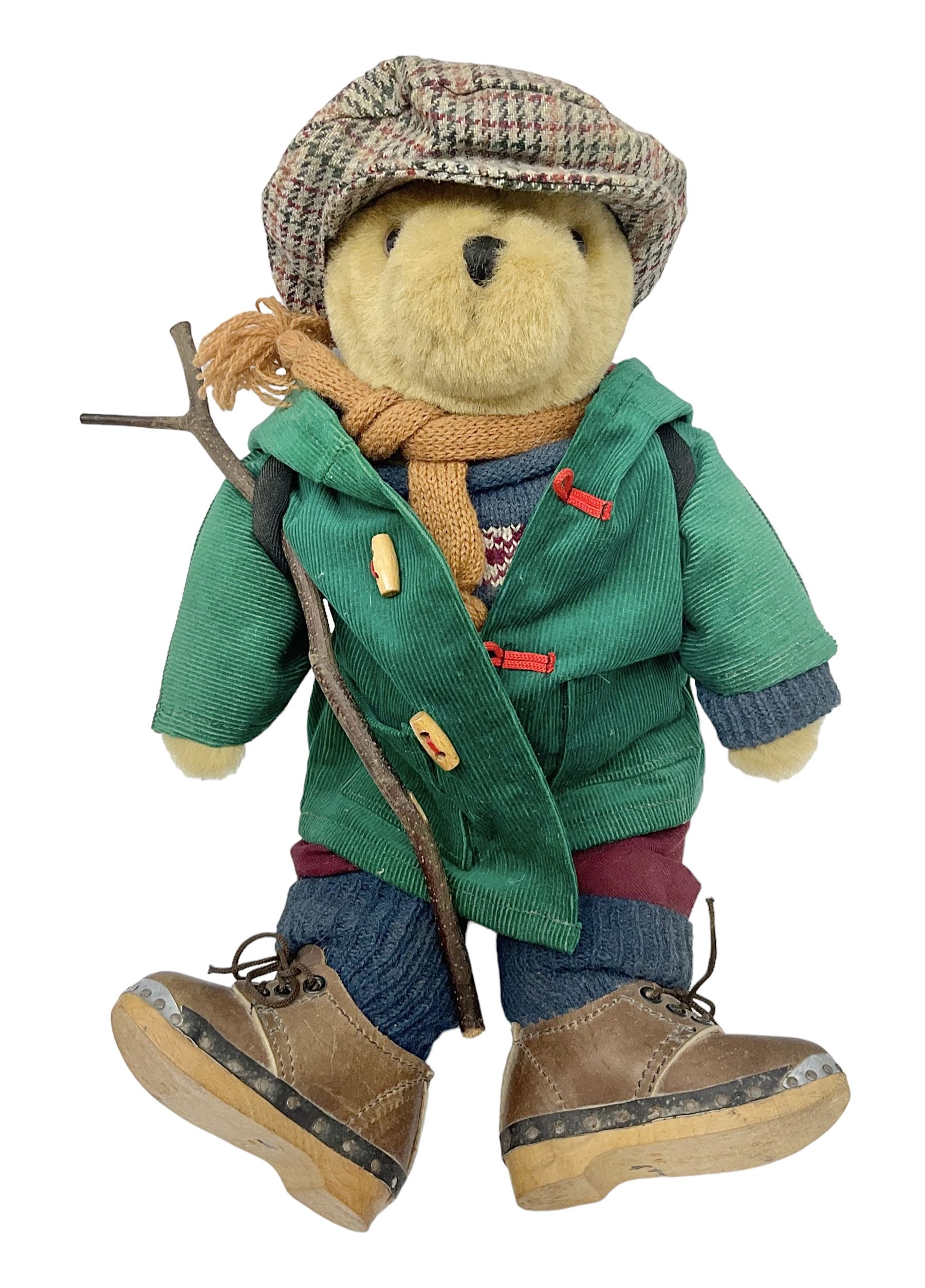 Lakeland Bears teddy bear, titled 'Walkright', dressed as a hiker in green corduroy duffle coat over fair isle jumper, trousers and knit socks, complete with leather clogs with wood soles, walkers thumb stick, knitted scarf, flat cap and rucksack housing original tag and map, H50cm