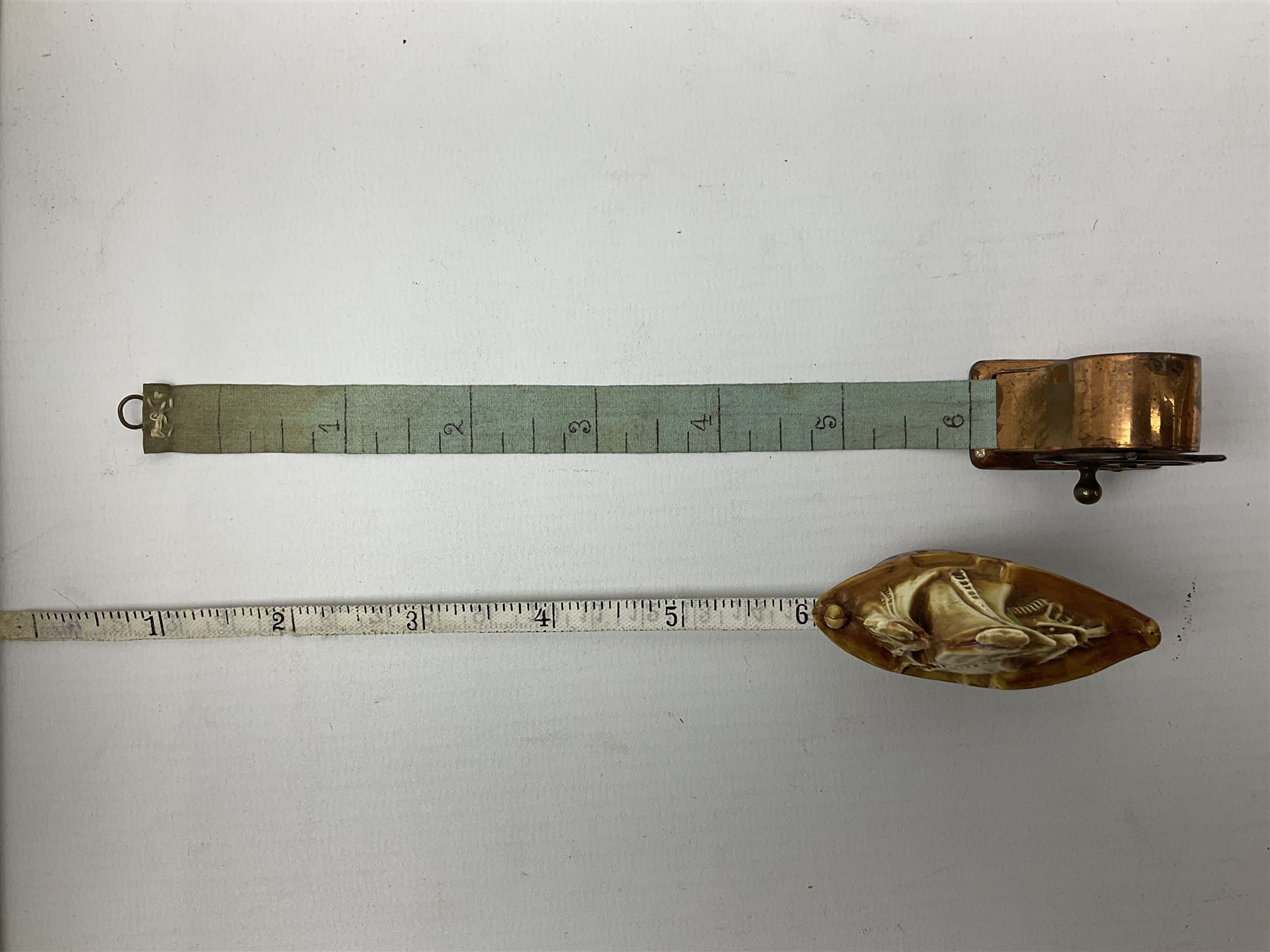 Copper tape measure in the form of a ship`s wheel, marked 'Rd. 128885' to the front, and a celluloid tape measure in the form of a galleon, wheel H4cm