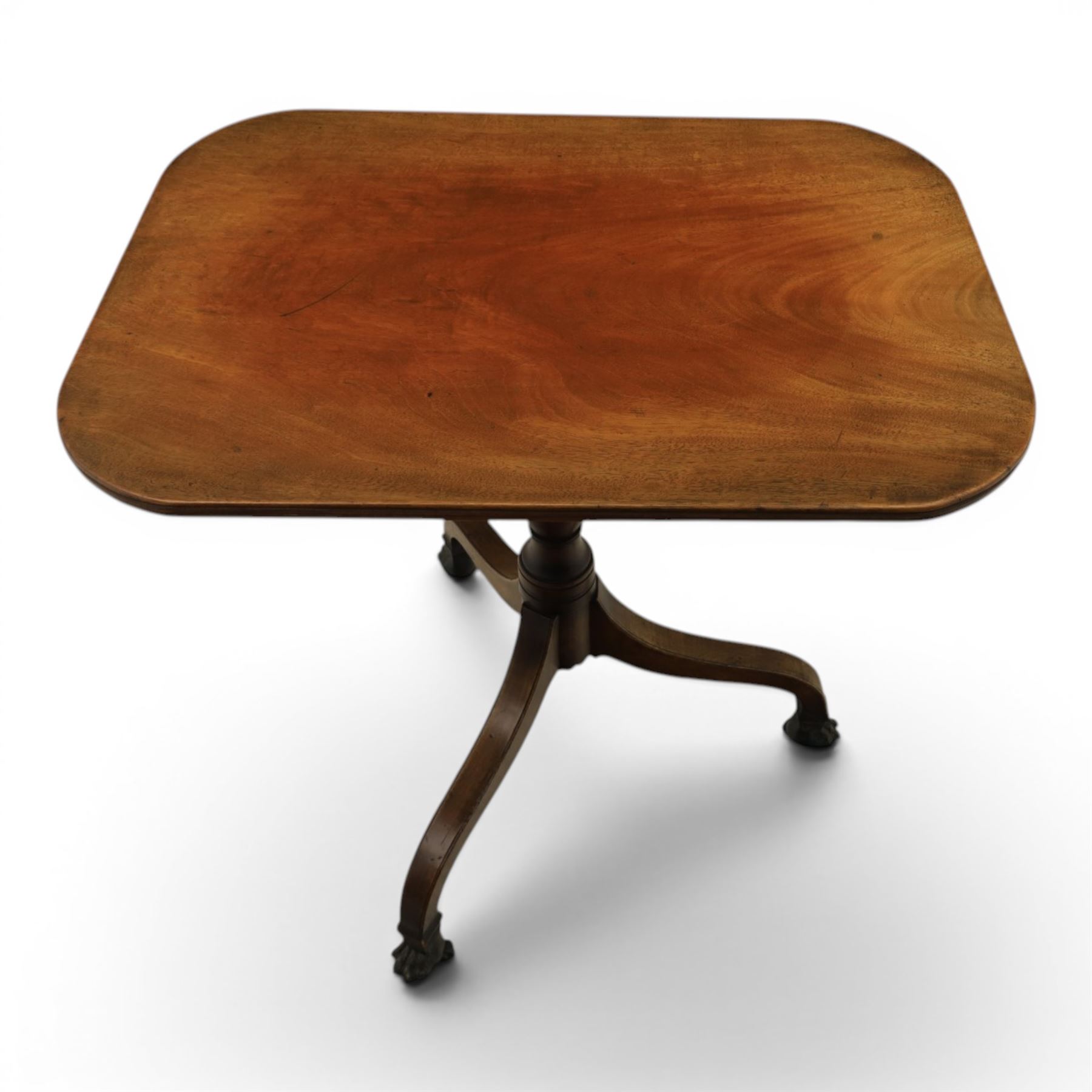 George III mahogany tripod table, rounded rectangular tilt top, raised on a turned column, on splayed supports, terminating brass claw feet above castors