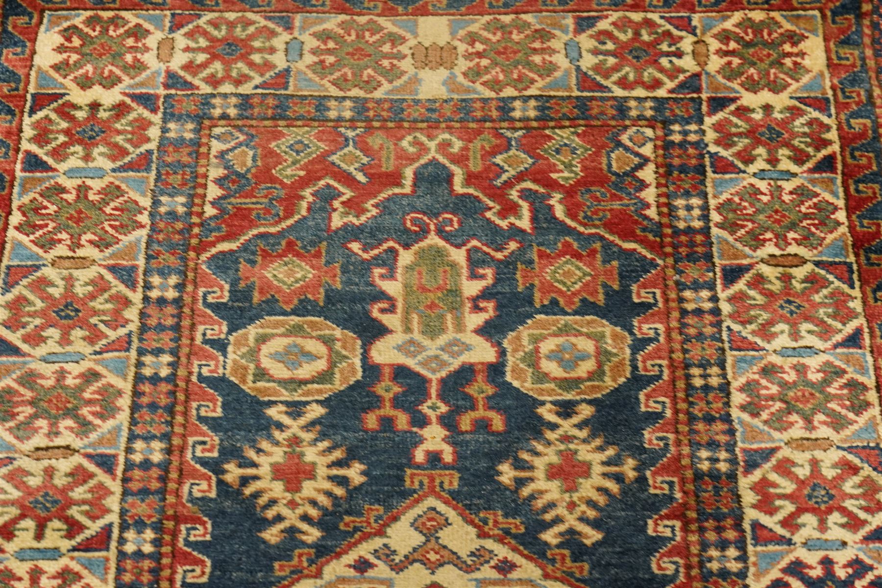 Caucasian hand-knotted runner, dark navy ground with three ivory geometric medallions surrounded by stylised flowerheads and angular motifs in madder red, green and ivory, enclosed by repeating geometric borders